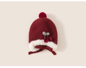 Détail du bonnet en tricot rouge pour bébé avec protège-oreilles et décor de cerises