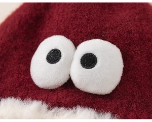 Détail du bonnet d'hiver en tricot rouge pour enfants avec bord en peluche et grands yeux