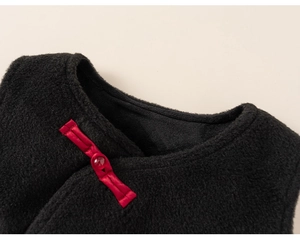 Close-up of black fleece texture featuring a traditional red Chinese frog button closure