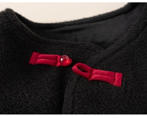 Detail of a vintage Chinese knot button with red bead on a black velvet vest
