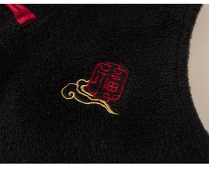 Detailed view of the red Fu character embroidery and golden clouds on black plush fabric