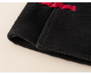 Close-up of traditional red Chinese frog buttons on thick black wool fabric for kids