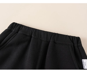 Close-up of elastic waistband on children's black knitted joggers with brand tag