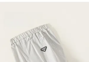 Detail of grey kids cargo pants featuring elastic waistband and leather logo patch