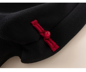 Detailed close-up of a traditional Chinese red knot button on black knitted fabric