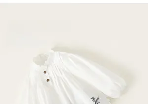 Detailed view of girls cream white cotton shirt with wood buttons and floral embroidery