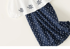 Detail of white embroidered shirt with elastic cuffs and floral ruffle pants
