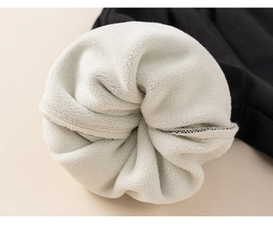 Detailed macro view of soft white fleece lining and black knit fabric on kids warm vest