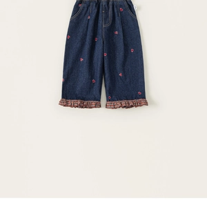 Détail du pantalon en jean pour filles avec broderie coeur et ourlet à carreaux volanté