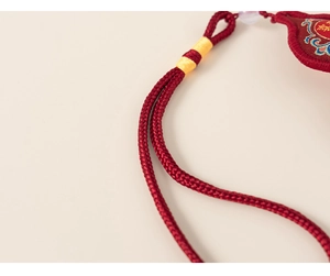 Macro detail of red woven cord with yellow thread wrap and purple bead for kid outfit