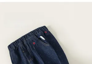 Détail de pantalon en jean bleu foncé pour filles avec broderie cœur rouge et taille élastique