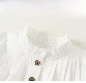 Close-up of girls white cotton shirt showing lace collar and pleated details with buttons