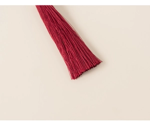 Detailed close-up of wine red tassels with fine silk texture for children's festive clothing