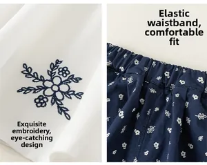 Detail of girls' white floral embroidered shirt and navy elastic waist floral pants