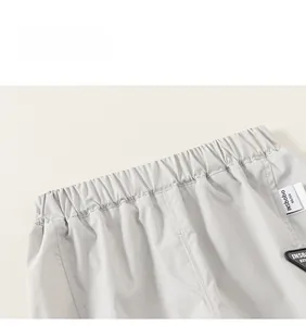 Detail of light gray kids cargo pants showing elastic waistband and brand woven label