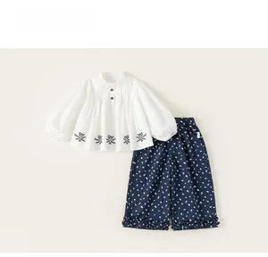 Detailed view of white cotton shirt with lace collar and floral printed trousers