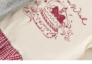 Detail of baby girl shirt featuring a crown rabbit print and red checkered hem detail