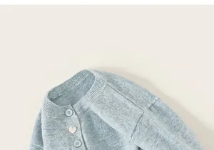Detail van blauw gebreid vest met geribbelde halslijn en hartvormig knoopdetail
