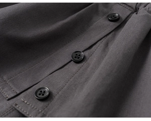 Macro detail of dark grey twill fabric with three black four-hole buttons and fine stitching