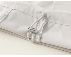 Close-up of adjustable drawstring and plastic toggle on light gray cargo pants hem