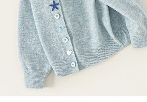 Detail van blauw gebreid vest met diverse decoratieve knopen en ribgebreide boorden