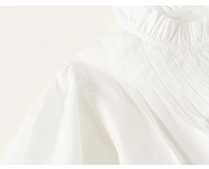 Detailed view of white cotton girls shirt with ruffles and pleated design details