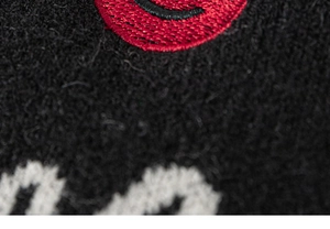 Macro detail of the premium red and white 3D embroidery on black knitted fabric