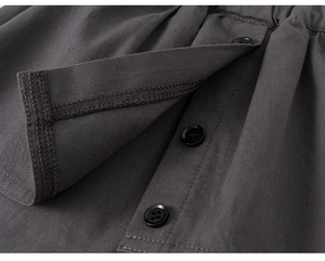 Detail of dark grey twill fabric featuring three black round buttons and precise stitching