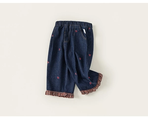 Détail de pantalon en jean fille avec broderie de cœur rouge et bordure dentelle