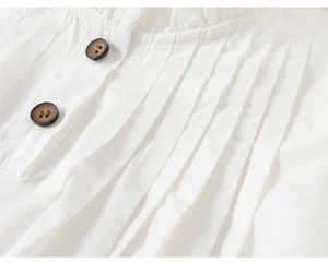 Detailed view of white cotton shirt with vertical pleats and wooden buttons