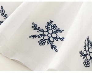 Detailed close-up of dark blue floral embroidery on white cotton fabric for kids