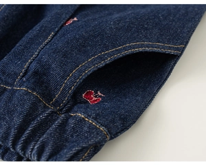 Détail du jean enfant bleu foncé avec taille élastique et broderie cœur rouge