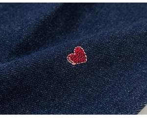 Vue détaillée de broderies cœur rouge sur tissu denim bleu foncé pour pantalon fille