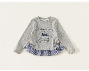 Detail of grey long sleeve girl shirt featuring gingham ruffles and bow accents