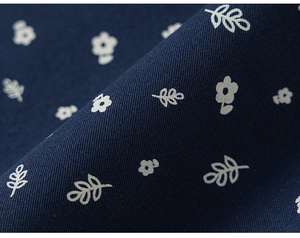 Close-up of navy blue twill fabric with delicate white floral prints and leaf patterns