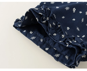 Detail of dark blue floral cotton fabric with ruffled edges and white flower patterns