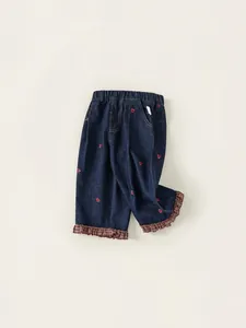 Jean fille en denim bleu foncé avec broderies cœurs et ourlets à carreaux volantés