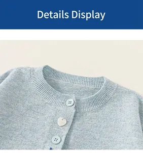 Detailopname van het blauwe gebreide vest met hartvormige parelknoop en zachte stof