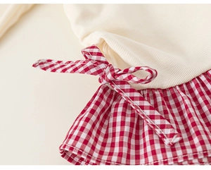 Detail of girls' ribbed top with red gingham pleated hem and bow decoration
