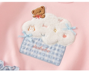 Detail van roze katoenen sweatshirt met teddybeer borduurwerk en blauwe strik