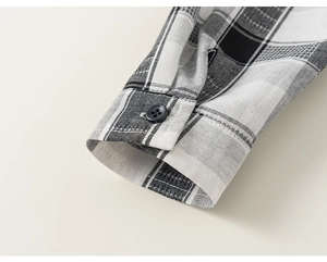 Detail of checkered shirt cuff with a resin button and precise stitching texture