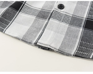 Detailed close-up of plaid shirt hem with neat stitching and black button