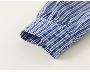 Detailed close-up of blue gingham cotton fabric and refined stitching on shirt cuff