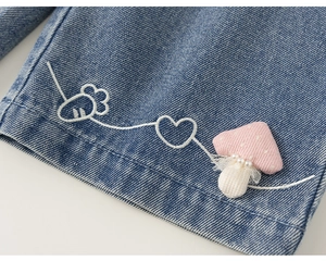 Dettaglio dell'orlo in denim per bambini con carota ricamata e toppa a fungo decorata