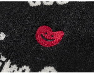 Macro shot of red heart embroidery with black smiley face on premium knitted fabric