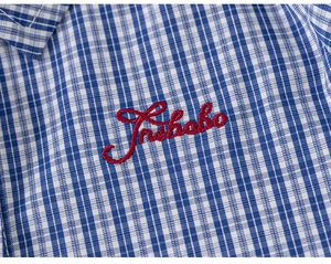 Detailed macro view of the blue plaid cotton fabric with high-quality red letter embroidery