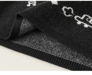 Close-up of black knit fabric with white musical notes and car patterns for boys clothing