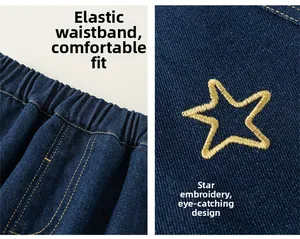 Detail view of elastic waistband and yellow star embroidery on dark blue denim jeans