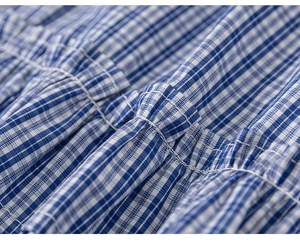 Close-up of blue and white checkered fabric featuring ruffled pleats and fine stitching