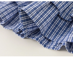 Detailed macro view of the blue gingham fabric texture and ruffled hem with fine stitching